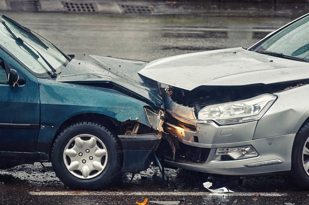 Autounfall auf nasser Fahrbahn bei Regen, Frontalzusammenstoß – Seitenansicht. Zwei Autos nach Frontalzusammenstoß beschädigt, Autounfall. Autounfall auf der Straße, beschädigte Autos nach der Kollision. Verstoß gegen die Verkehrsregeln